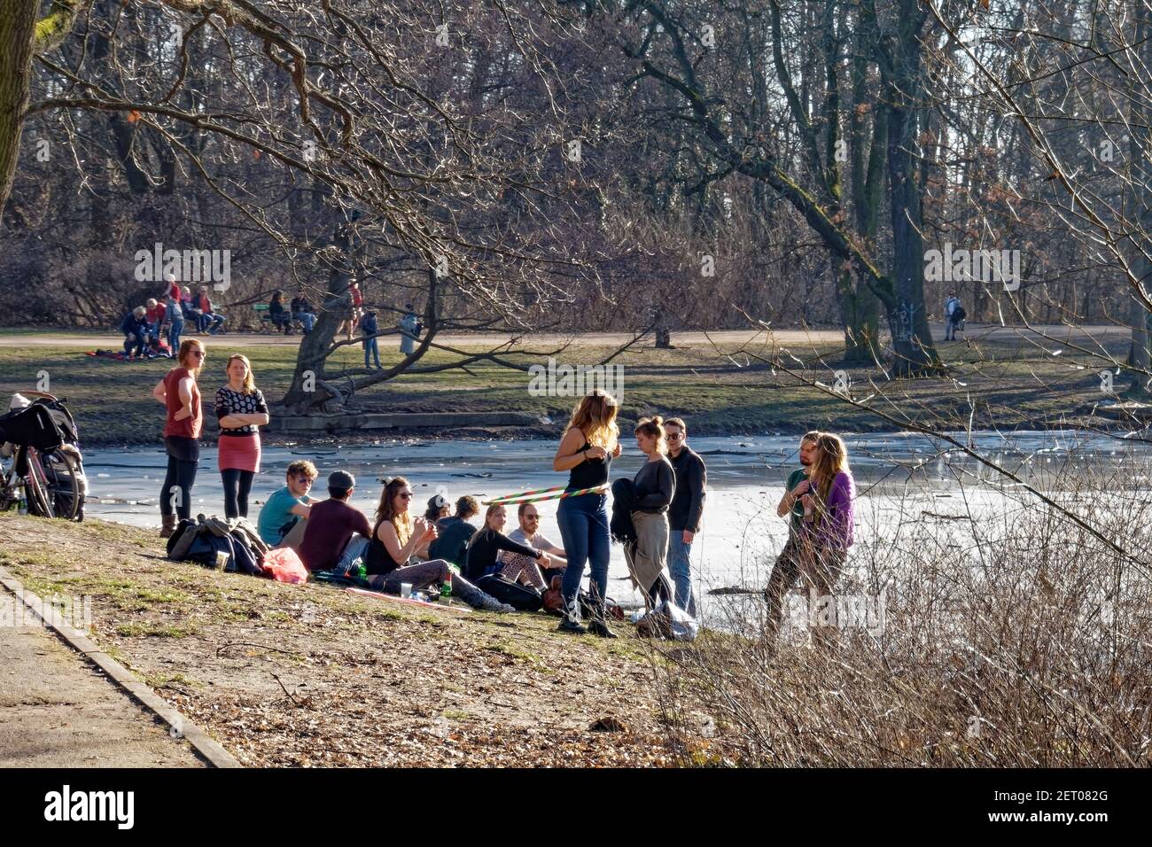 Vorfruehling in Berlin Mitte Februar 2021 , Treptower Park, Karpfenteich, Junge Leute geniessen das milde Fruehlingswetter .Frau mit Hula-Hoop-Reifen Stockfoto