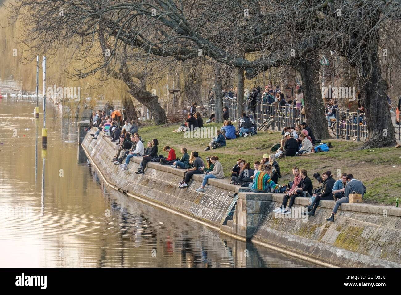 Junge Leute sitzen am Landwehrkanal in Kreuzberg, Urbanhafen, Berlin, Vorfrühling, Lockdown, Aha-Regeln, Stockfoto