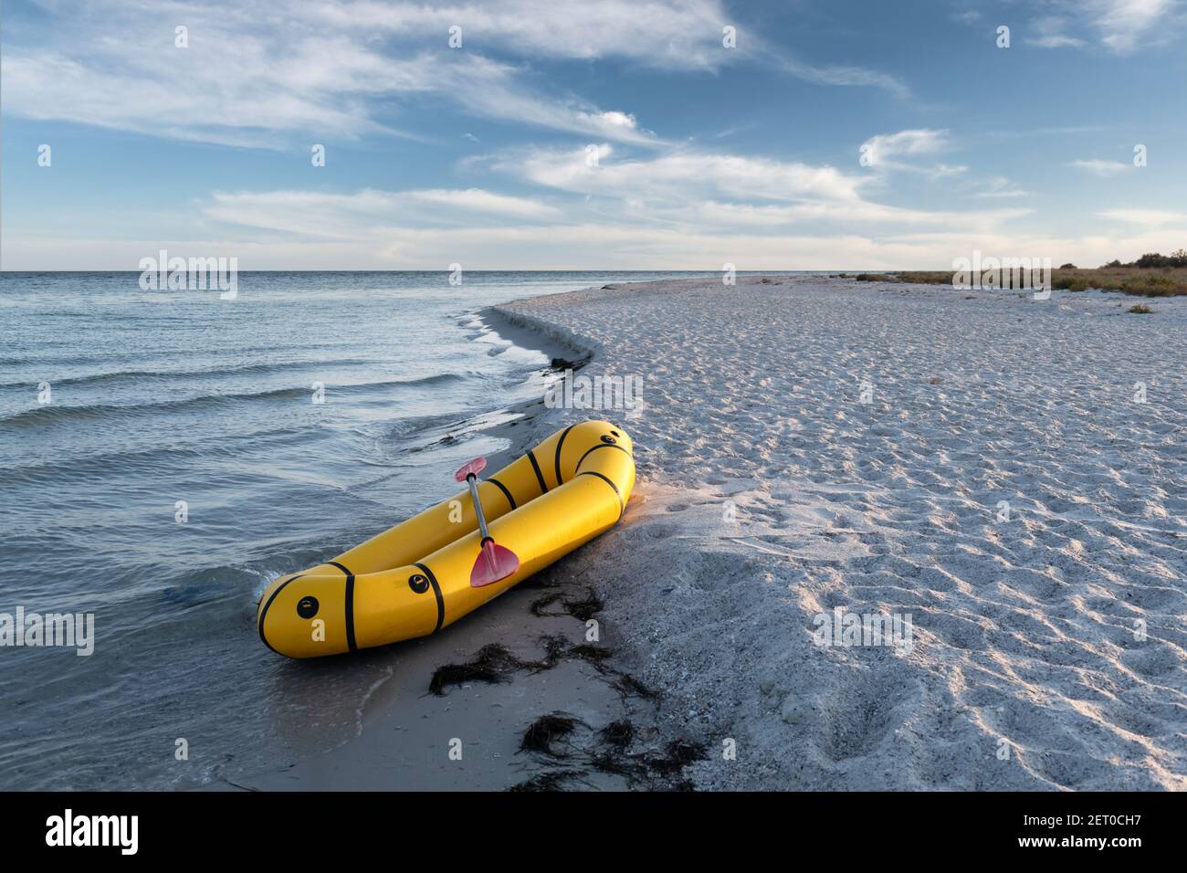 Gelbes Packfloß Gummiboot mit roter Pfanne an einer Küste. Packrafting. Aktives Lebenskonzept Stockfoto