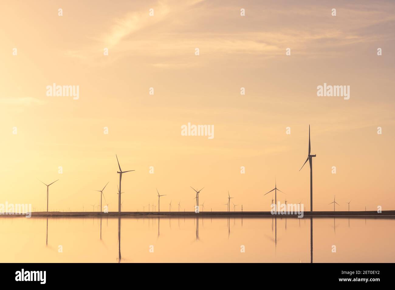 Ruhige, minimalistische Landschaft mit Reihen von Offshore-Windkraftanlagen, die sich im Meerwasser spiegeln. Industrielle Landschaftsfotografie Stockfoto