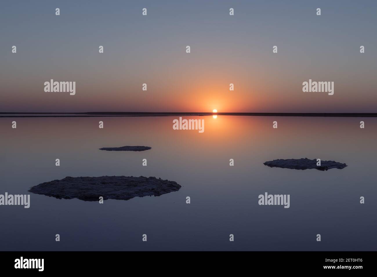 Ruhige minimalistische Landschaft mit glatter Oberfläche des rosa Salzsees mit ruhigem Wasser mit Horizont mit klarem Himmel in der Sonnenuntergangszeit. Einfache schöne natürliche ruhigen Hintergrund Stockfoto