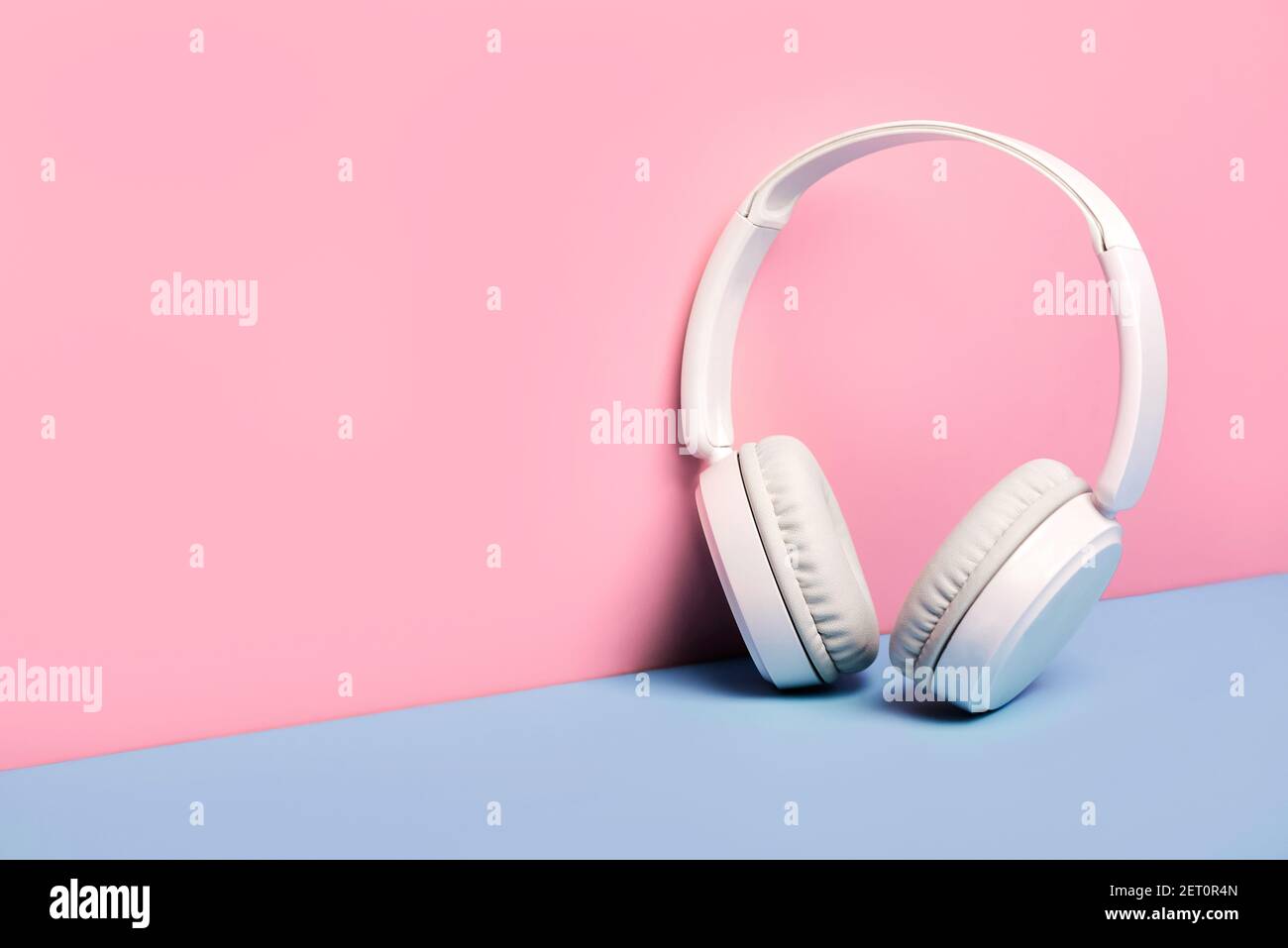Weißer drahtloser Bluetooth-Kopfhörer auf rosa und blauem Hintergrund Stockfoto