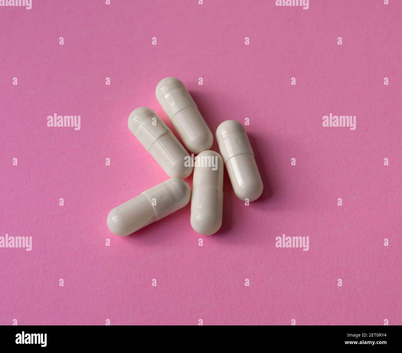 Weiße, große Kapseln, Pillen oder Tabletten auf einem rosa Hintergrund Stockfoto