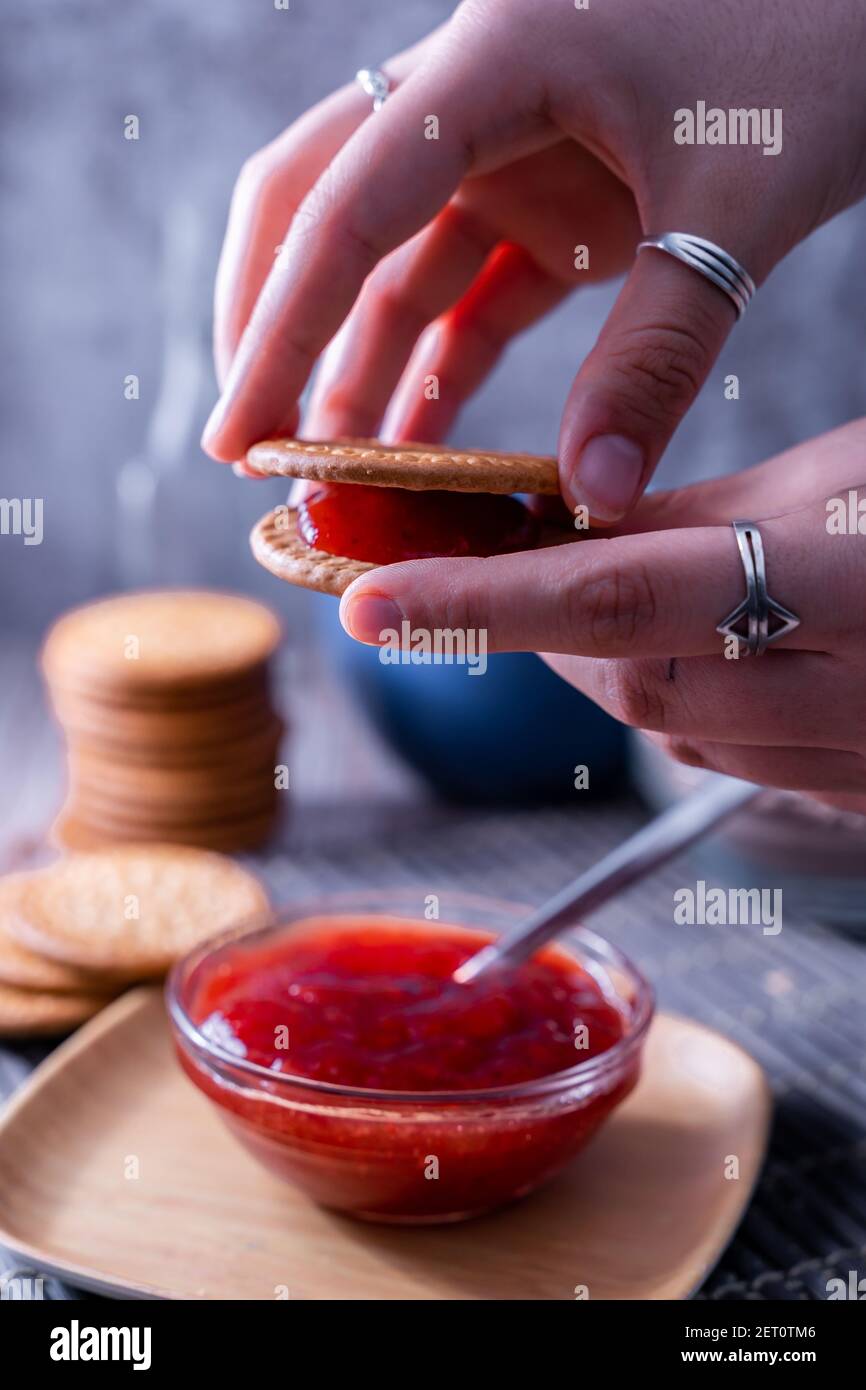 Eine vertikale Aufnahme von Händen halten frische Maria Cookie (galletas Maria) mit Erdbeermarmelade Stockfoto