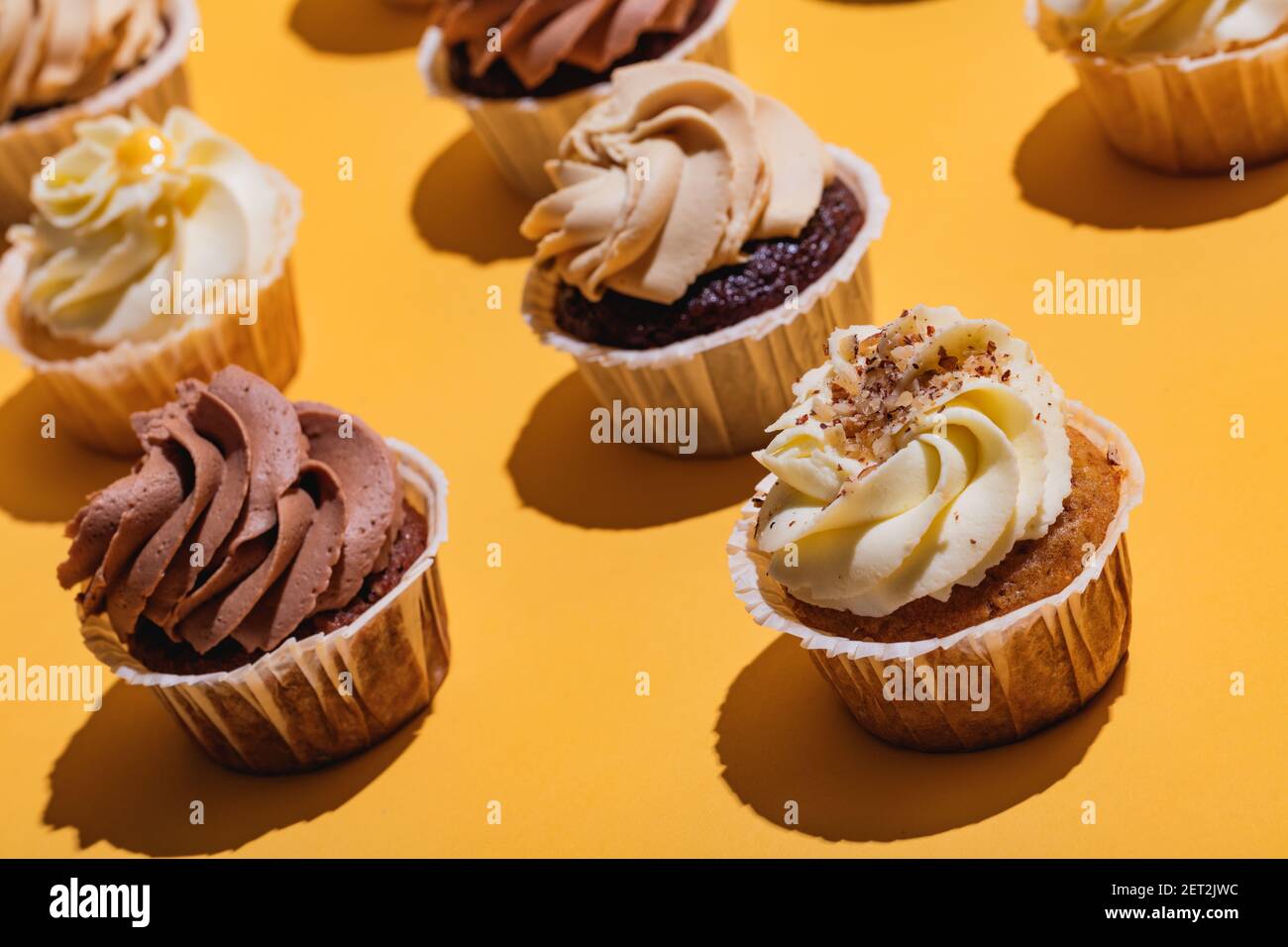 Cupcakes stehen auf gelbem Hintergrund in einer Nahaufnahme. Köstliche Leckerbissen. Stockfoto