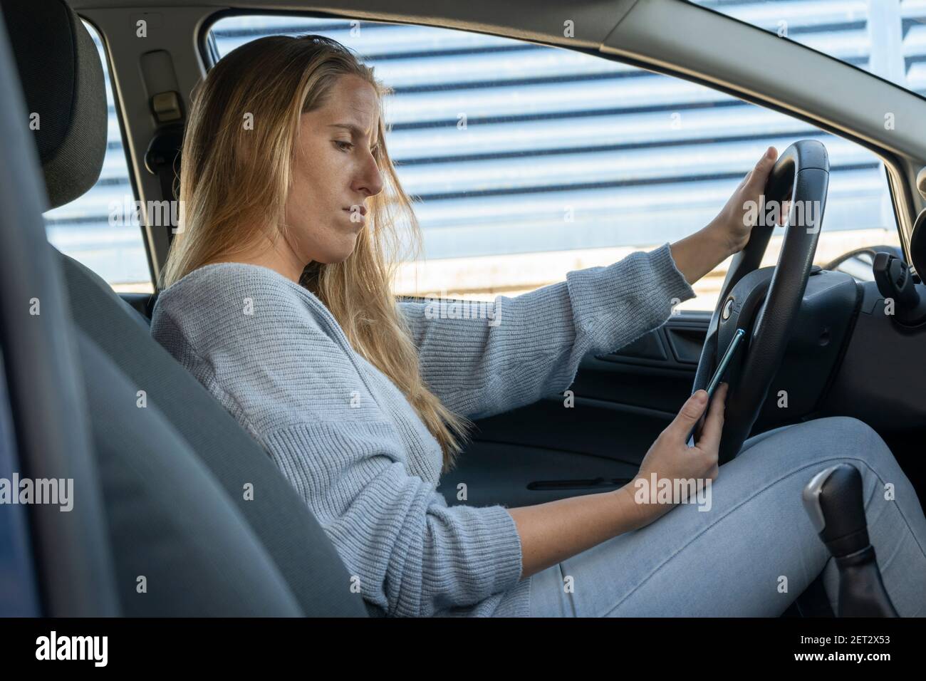 Junge schöne Frau suchen Telefon sitzen auf ihrem Auto, Sicherheit Antrieb concept.Using Smartphone fahren Fahrzeuge Lifestyle Stockfoto
