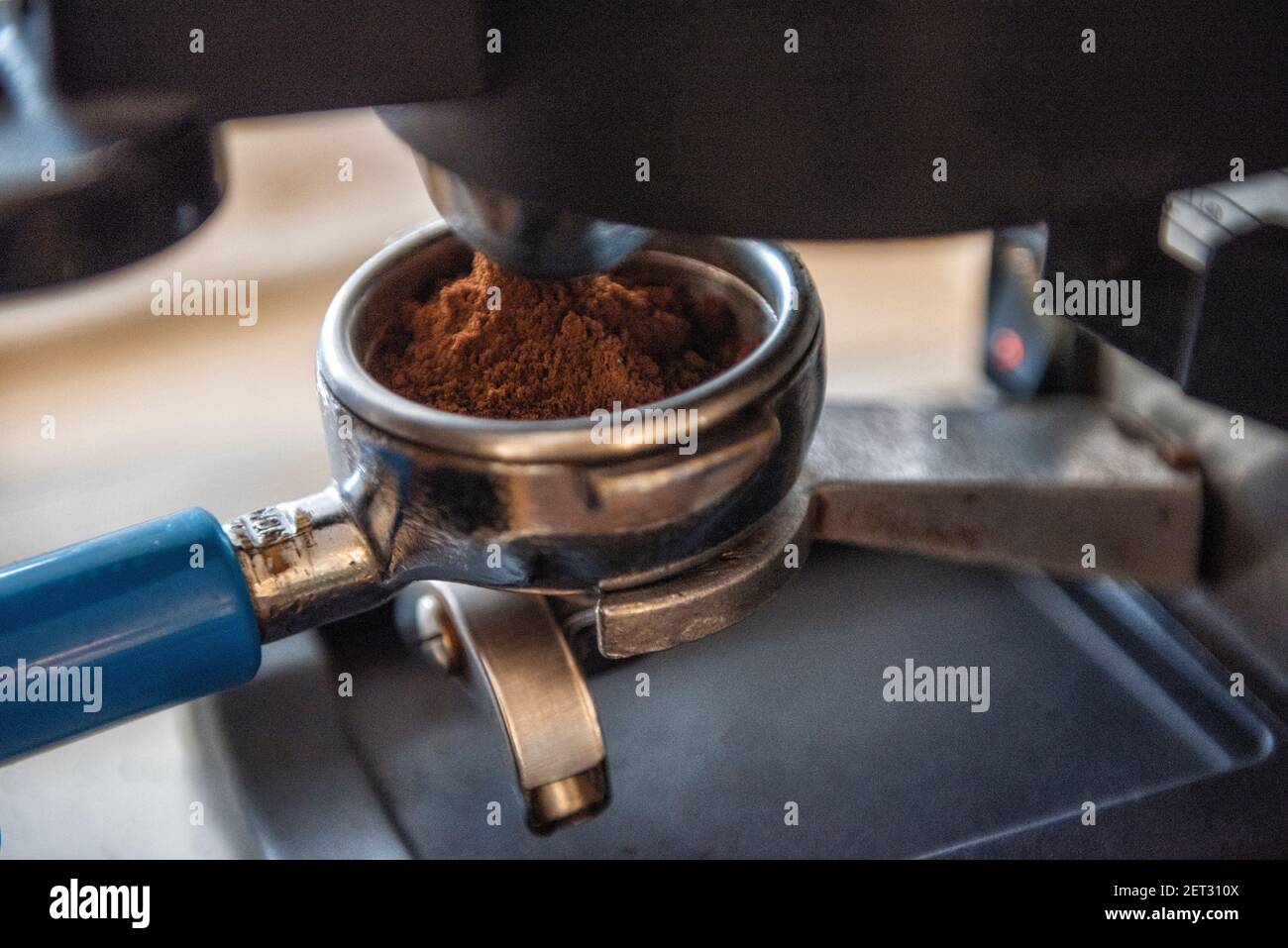 Nahaufnahme einer Person, die einen Portafilter an einen Espresso anschließt Maschine in einem Café Stockfoto