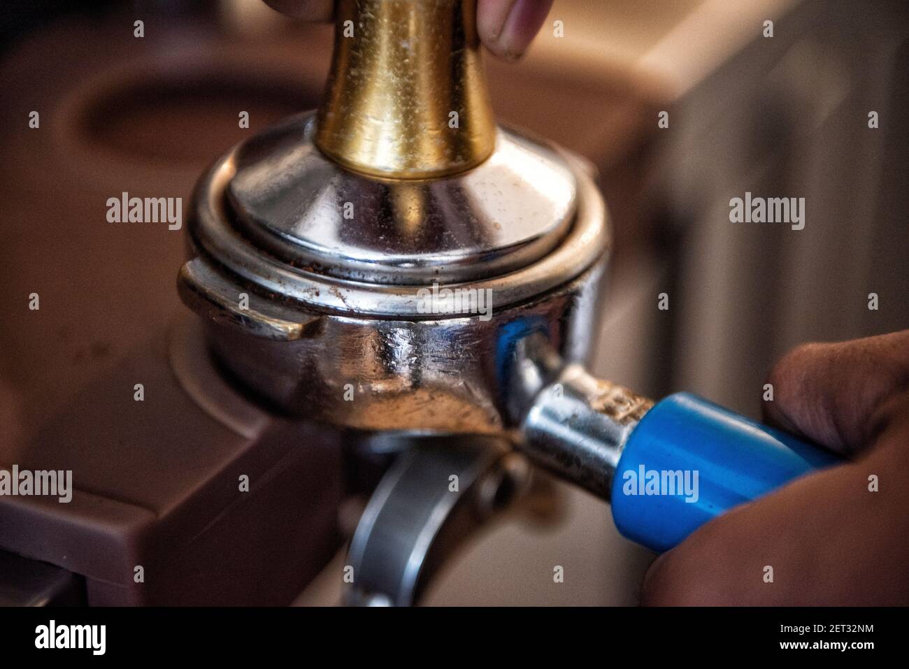 Nahaufnahme einer Person, die einen Portafilter an einen Espresso anschließt Maschine in einem Café Stockfoto