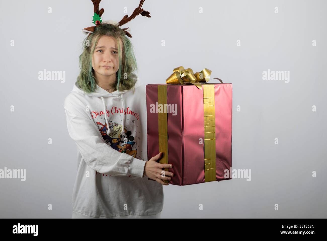 Foto von einem jungen Mädchen Modell in Hirsch Hörner Maske Ein großes Weihnachtsgeschenk halten Stockfoto