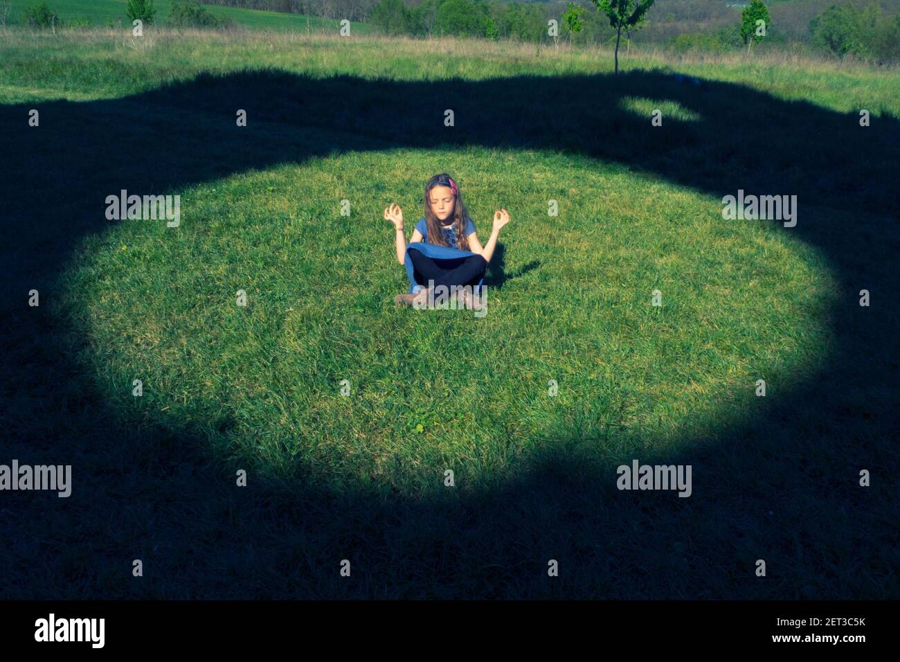 Mädchen sitzt auf dem Gras in einem Kreis meditieren Stockfoto