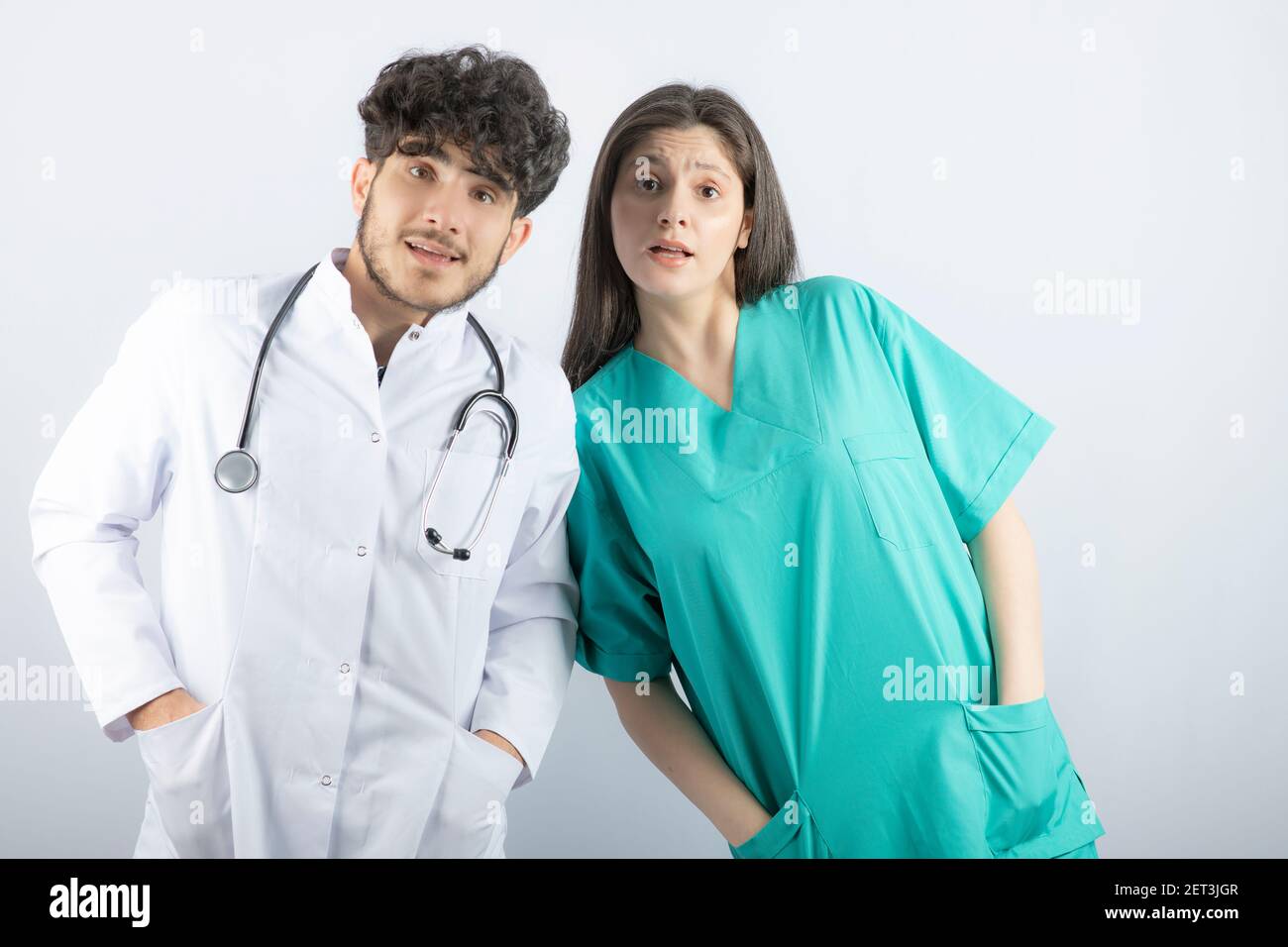 Frau und Mann Ärzte stehen und betrachten Kamera überraschend Stockfoto