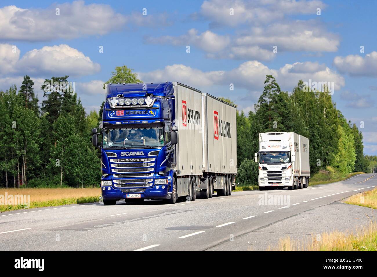 Zwei Scania-Gütertransportwagen, blaue DB Schenker im Vordergrund, transportieren im Sommer Güter auf dem Highway 10. Jokioinen, Finnland. 7. August 2020 Stockfoto