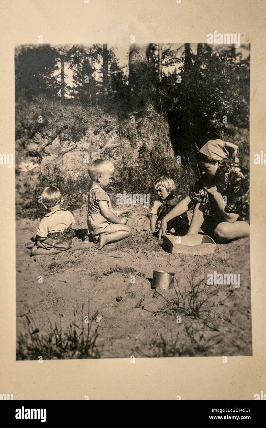 Deutschland - UM 1930s: Gruppenfoto von Mutter und Baum kleine Kinder sitzen im Garten. Vintage Archiv Art Deco Ära Fotografie Stockfoto
