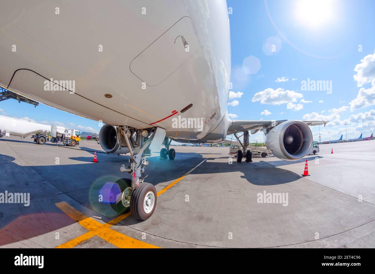 Sonniger Tag und Blendung am Flughafen, Blick auf das vordere Fahrwerk und den Flügel des Flugzeugs Stockfoto