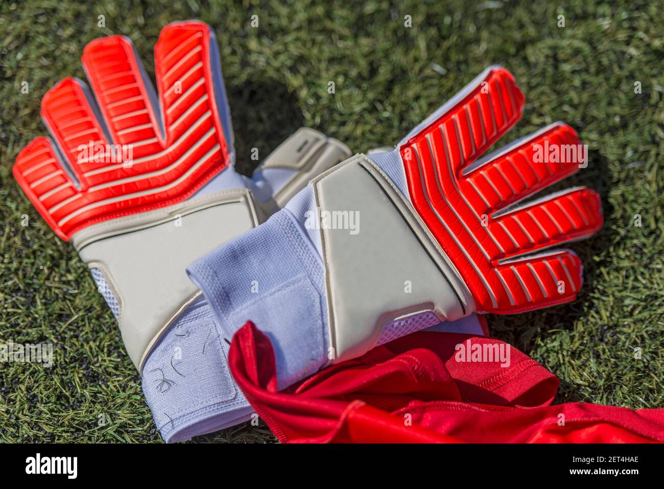 Leder Fußball Torwarthandschuhe, in rot und weiß, auf dem Kunstrasen Spielfeld. Stockfoto