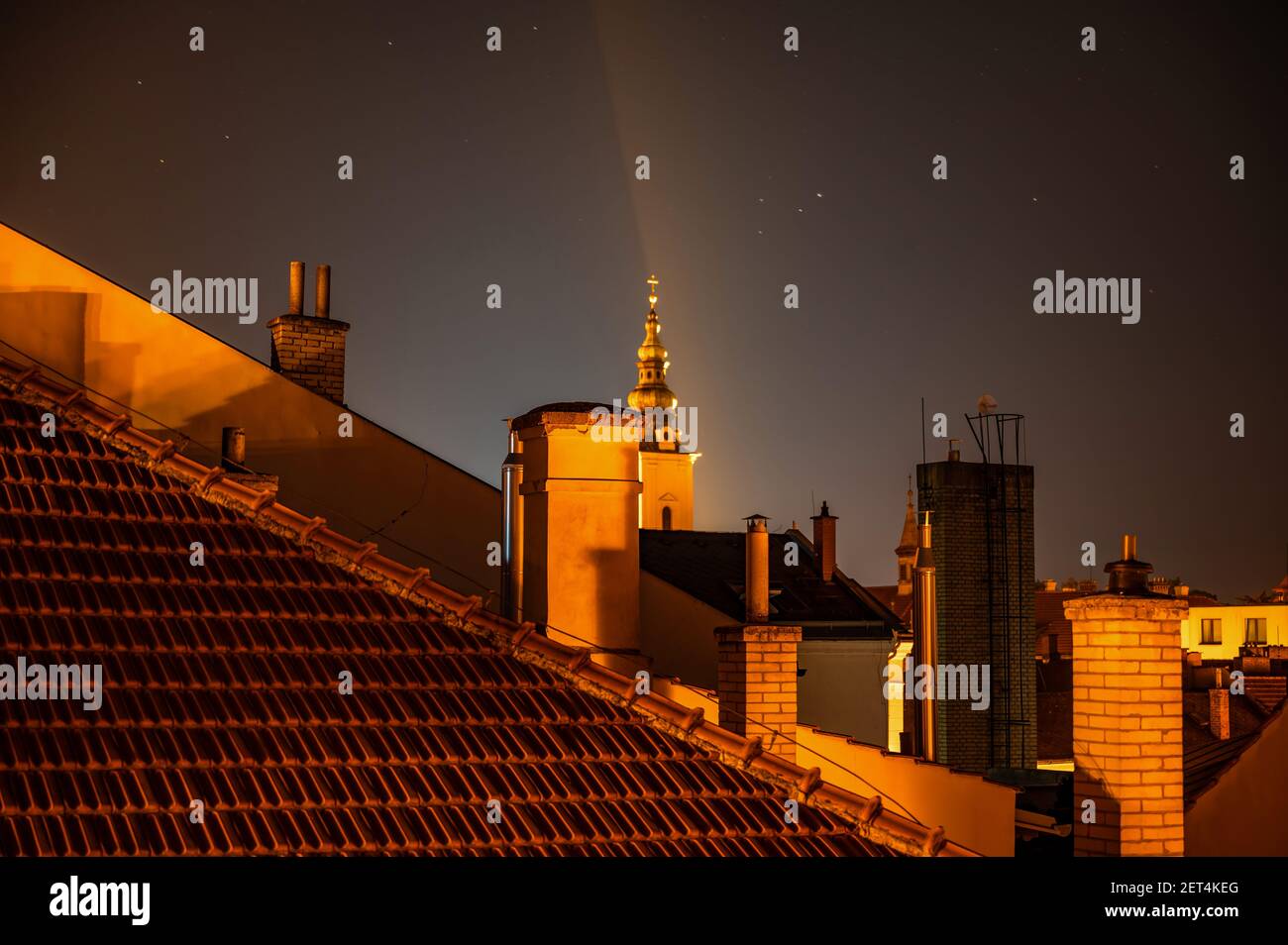 Dach der Häuser mit Kaminen und Kirchturm in der magischen Beleuchtung am Nachthimmel mit Stern, Uherske Hradiste Stadt, Tschechische republik. Stockfoto