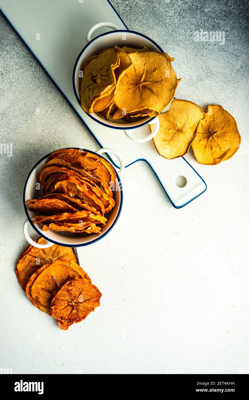 Schalen von getrockneten Apfel und Kaki Fruchtchips auf einem Tabelle Stockfoto
