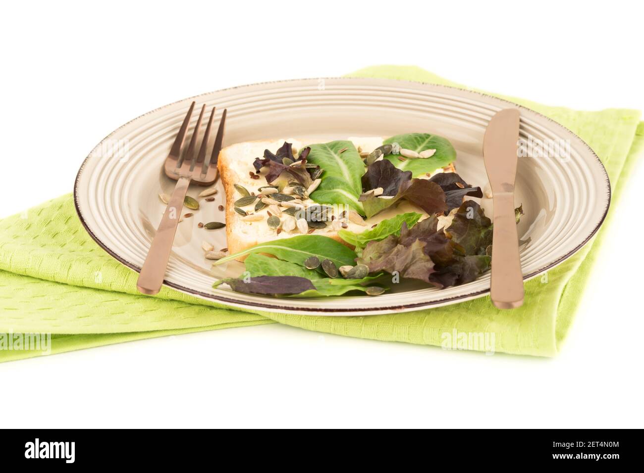 Sandwiches mit Butter, Samen und Salat auf Teller auf grünem Handtuch auf weißem Hintergrund. Stockfoto