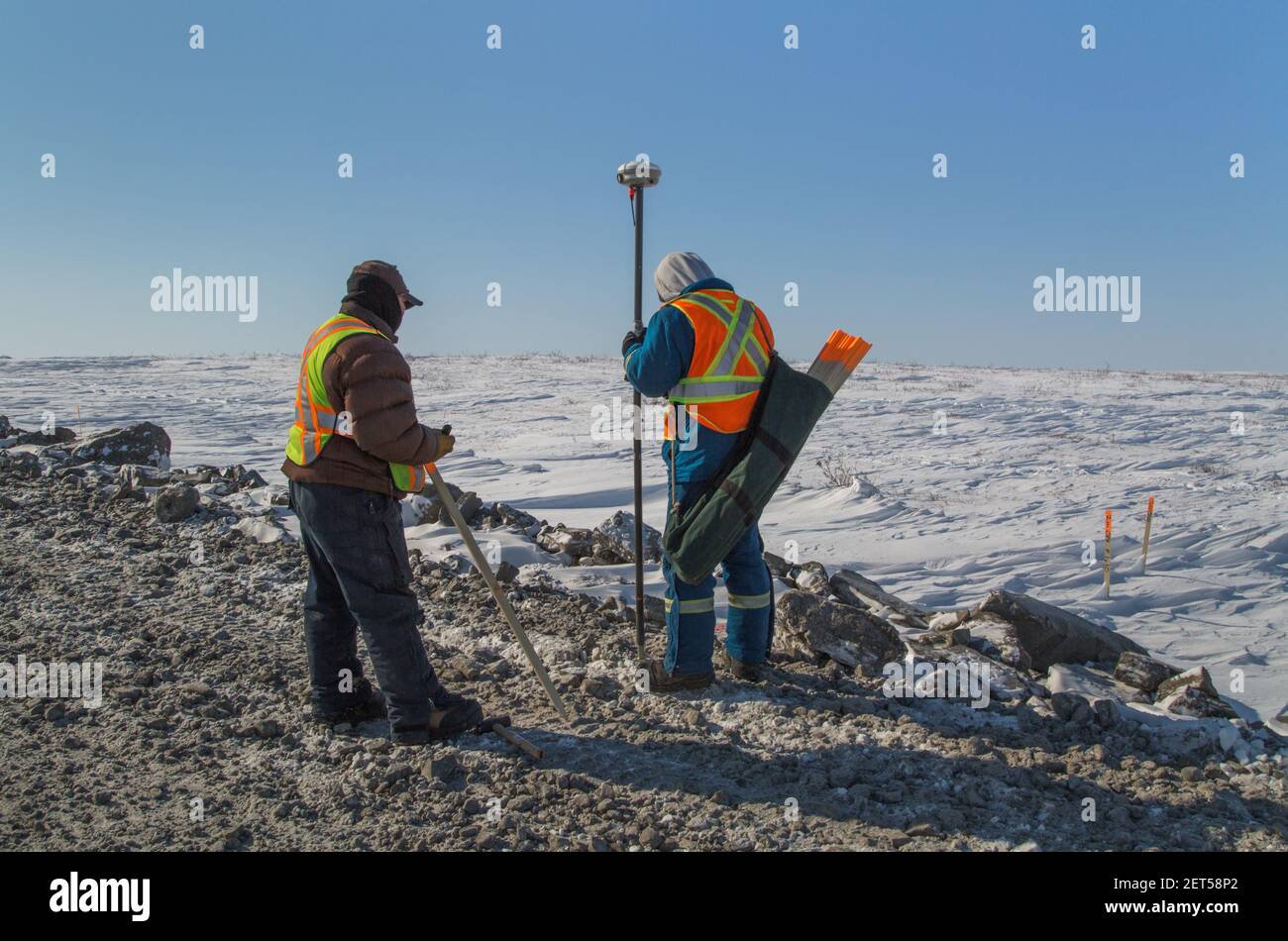 Zwei Arbeiter vermessen den Inuvik-Tuktoyaktuk Highway, Winterbau, Nordwest-Territorien, Kanadas Arktis, April 2014. Stockfoto