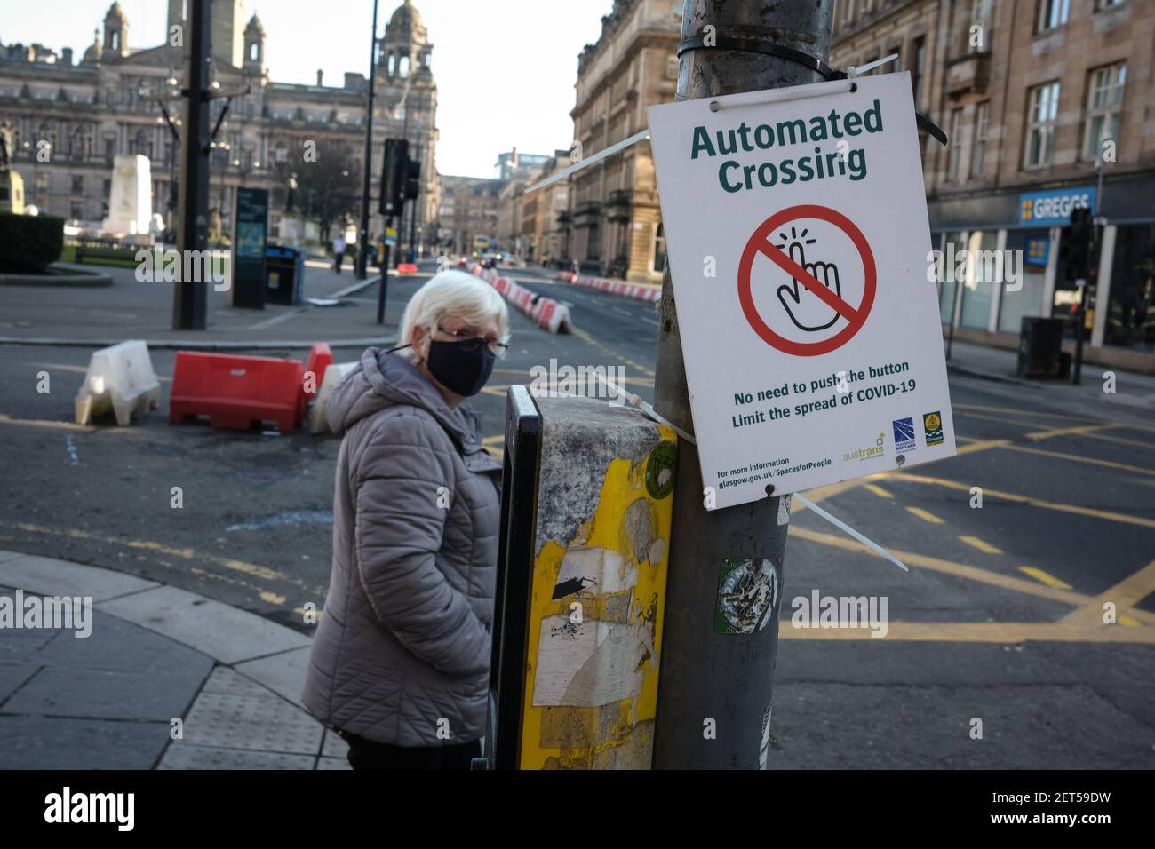 Glasgow, Großbritannien, am 1. März 2021. Eine Frau wartet an einer automatischen Kreuzung, die nicht den Knopf drücken muss und riskiert, Covid-19 in leeren Straßen des Stadtzentrums während der letzten Sperre zu erreichen. Mehr als 1,5 Millionen Menschen haben jetzt ihre erste Covid-19-Coronavirus-Impfung in Schottland erhalten. Foto: Jeremy Sutton-Hibbert/Alamy Live News. Stockfoto