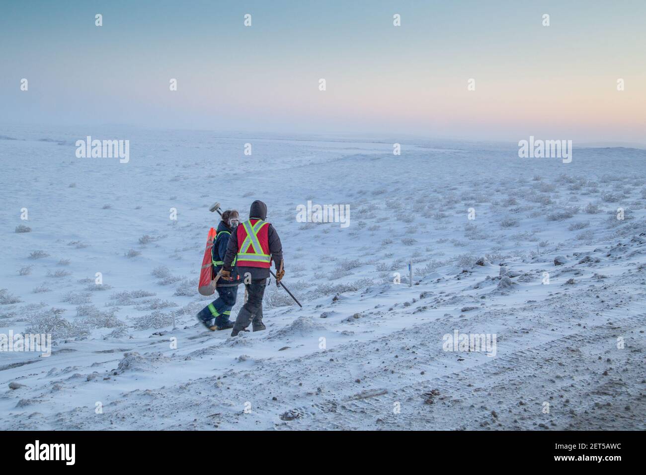 Zwei Arbeiter vermessen den Inuvik-Tuktoyaktuk Highway, Winterbau, Nordwest-Territorien, Kanadas Arktis. Stockfoto