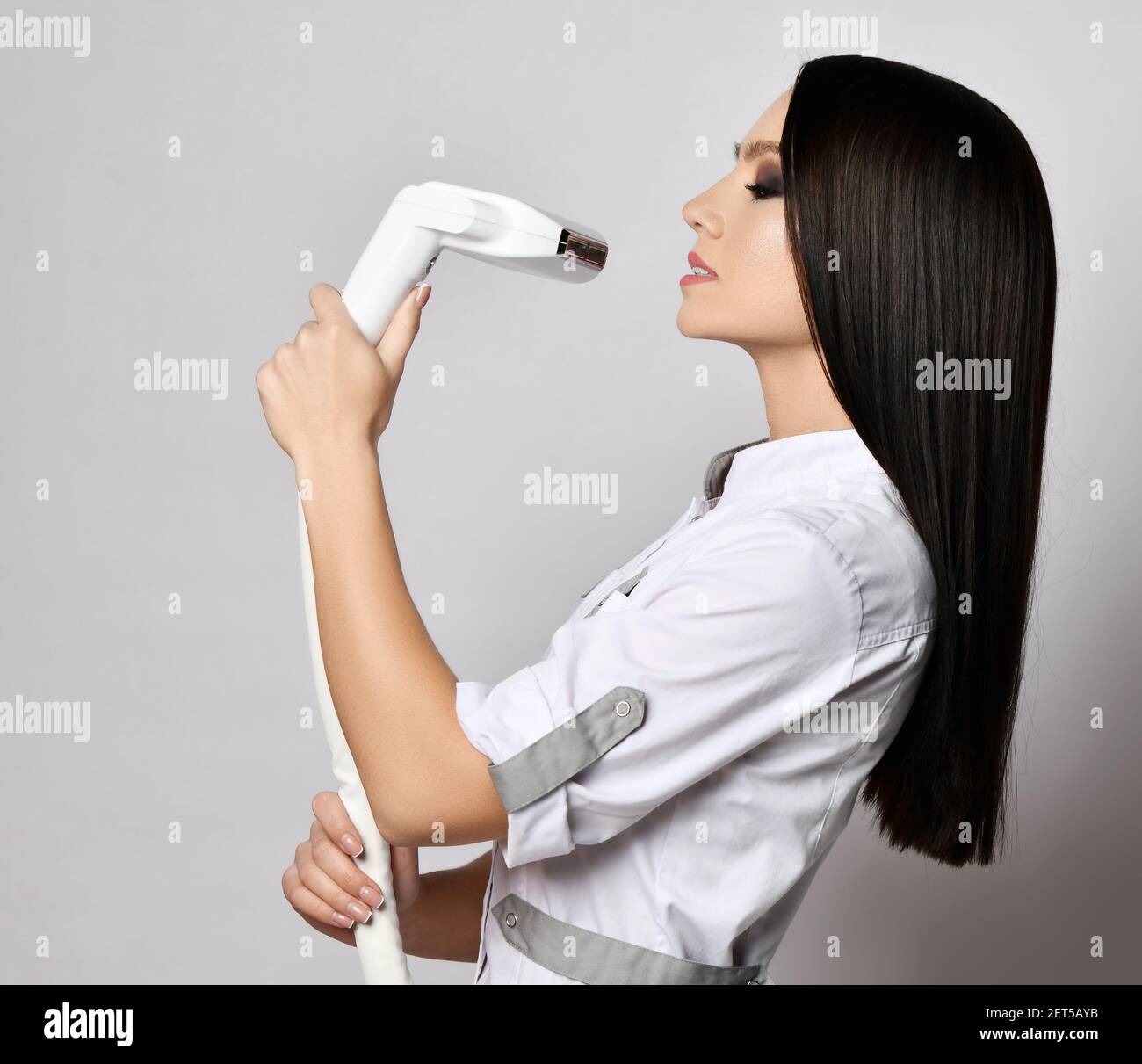Profil von jungen hübschen Brünette Frau in weißer Kleidung stehen Und Haltevorrichtungen für die Laser-Haarentfernung Stockfoto Profil von jungen hübschen Brünette Frau in weißer Kleidung stehen Und Haltevorrichtungen für die Laser-Haarentfernung Stockfoto