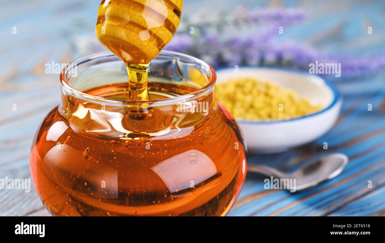Honig im Glas mit Honig Dipper auf Holzhintergrund Stockfoto