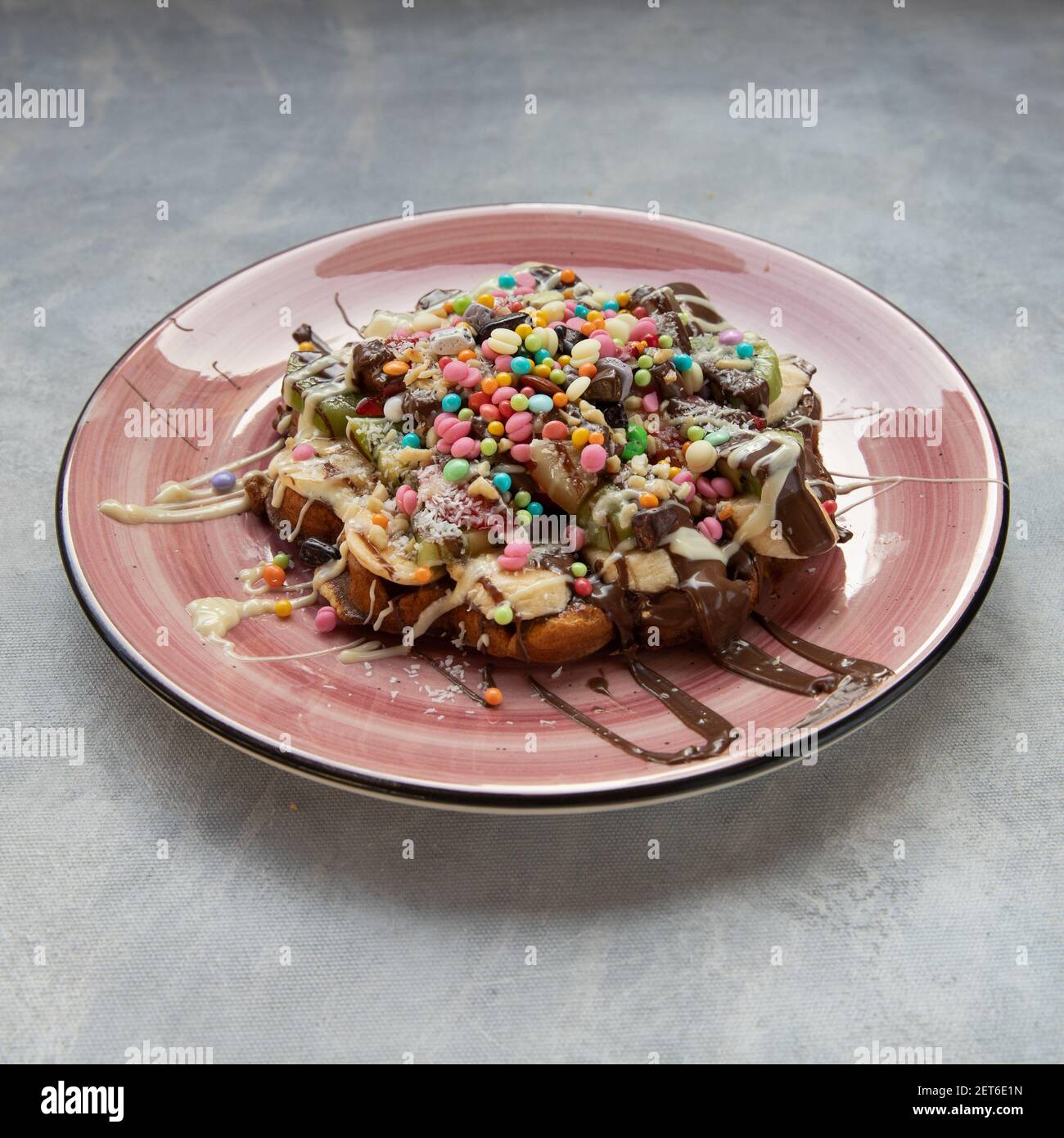 Eine köstliche Waffel serviert mit einem rosa Teller auf einem Grauer Hintergrund Stockfoto