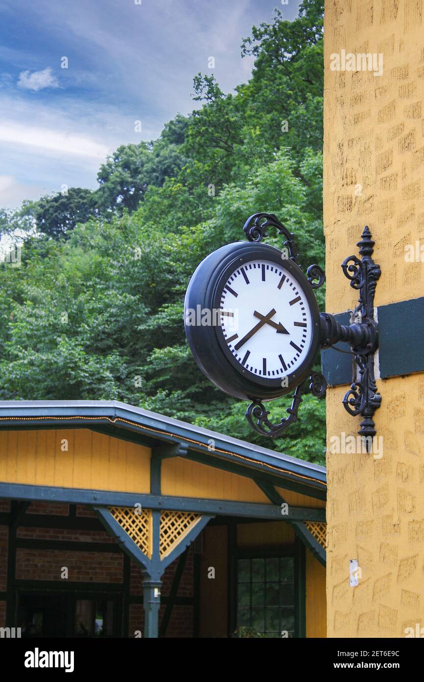 Eine vertikale Aufnahme einer Uhr im Vintage-Look, die auf dem montiert ist Wand außerhalb eines Gebäudes Stockfoto