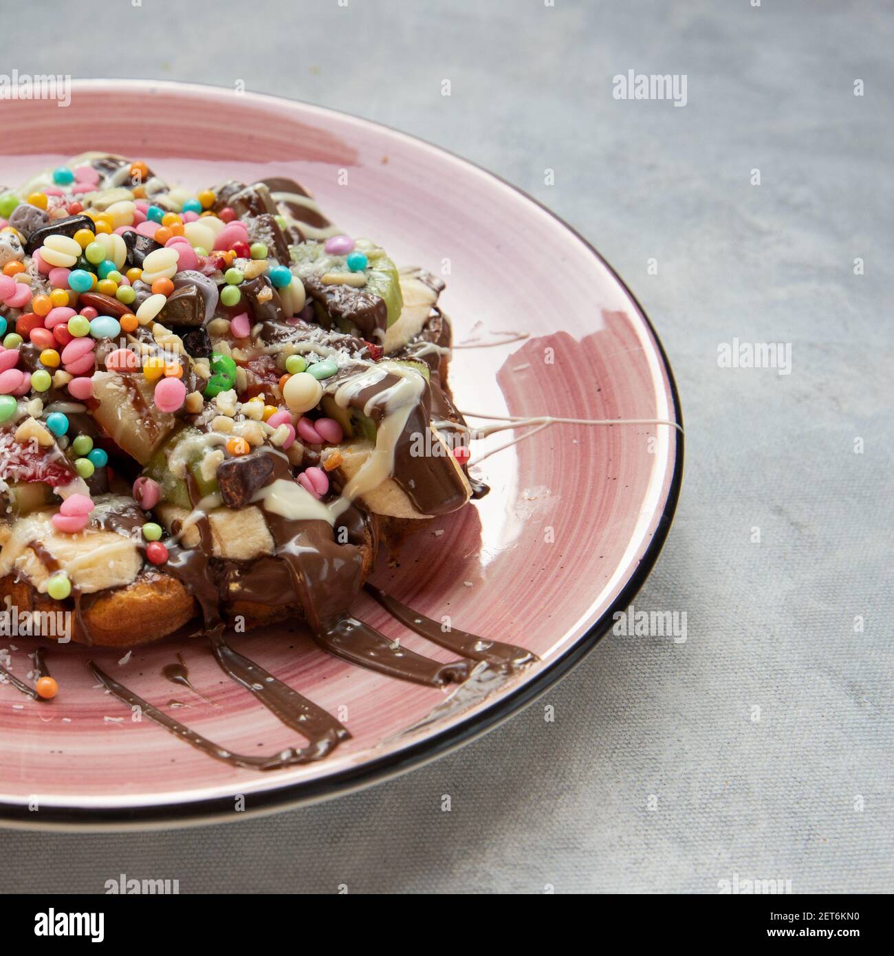Eine köstliche Waffel serviert mit einem rosa Teller auf einem Grauer Hintergrund Stockfoto