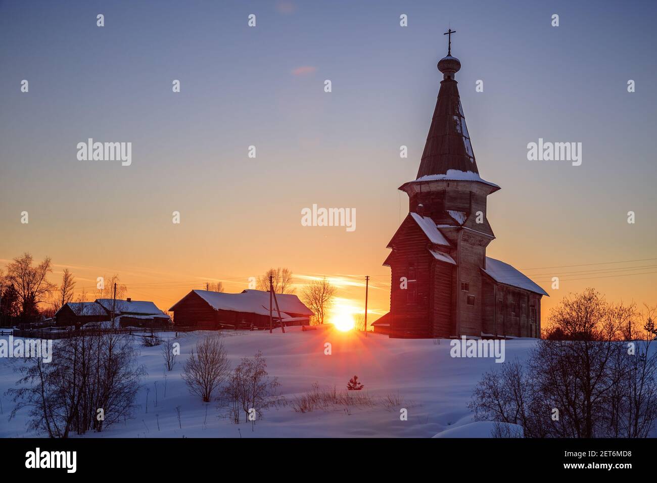 Winter ländliche Sonnenuntergangslandschaft. Die alte russische Holzkirche des Propheten Elia im Dorf Saminsky Pogost, Wologda Region, Russland Stockfoto