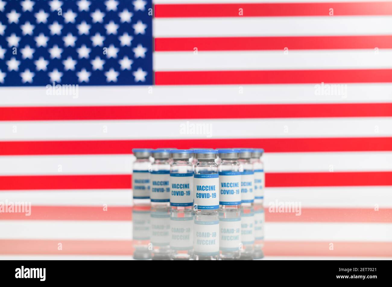 Gruppe von Vials mit einem neuen Coronavirus-Impfstoff mit einer amerikanischen Flagge im Hintergrund. Schutz vor Virusverbreitung Stockfoto