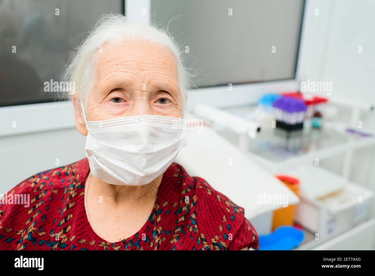 Porträt einer älteren Frau mit grauen Haaren und traurigen Augen, die eine medizinische Maske trägt. Stockfoto