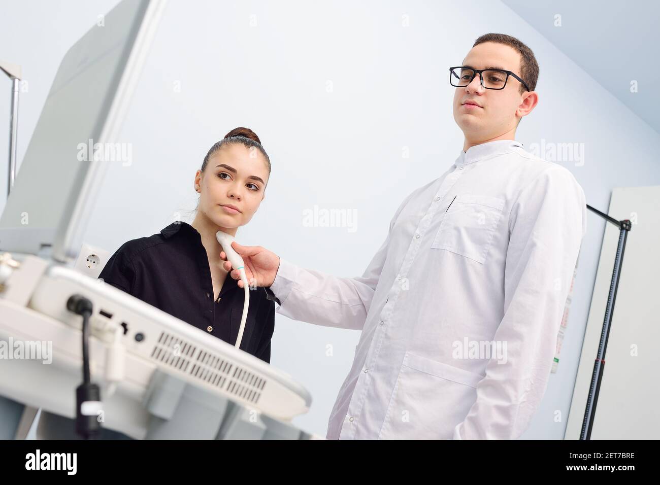 Der Arzt führt eine Ultraschalluntersuchung der Schilddrüse einer jungen, hübschen Frau in einer modernen Klinik durch. Prävention von Schilddrüsenkrebs. Stockfoto