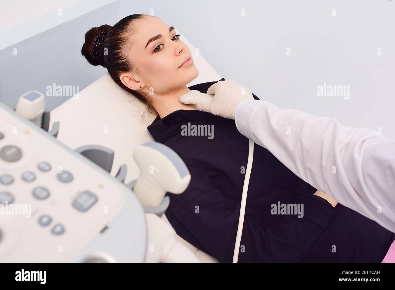 Der Arzt führt eine Ultraschalluntersuchung der Schilddrüse einer jungen, hübschen Frau in einer modernen Klinik durch. Prävention von Schilddrüsenkrebs. Stockfoto