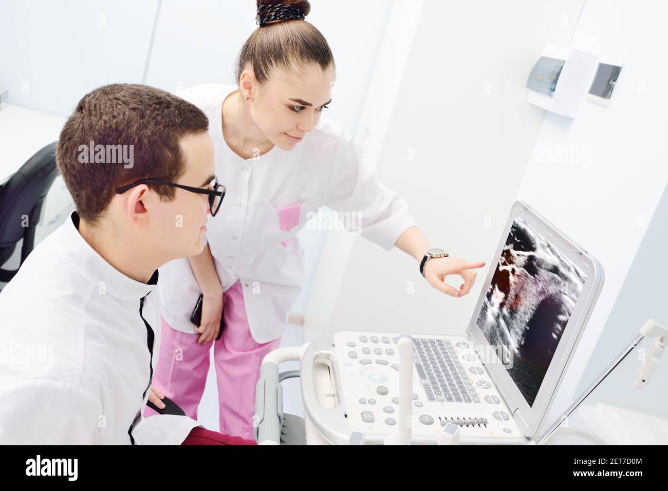Junge Ärzte-ein Mann und eine Frau-überprüfen und diskutieren das Ergebnis Einer Ultraschalluntersuchung der Schilddrüse Stockfoto