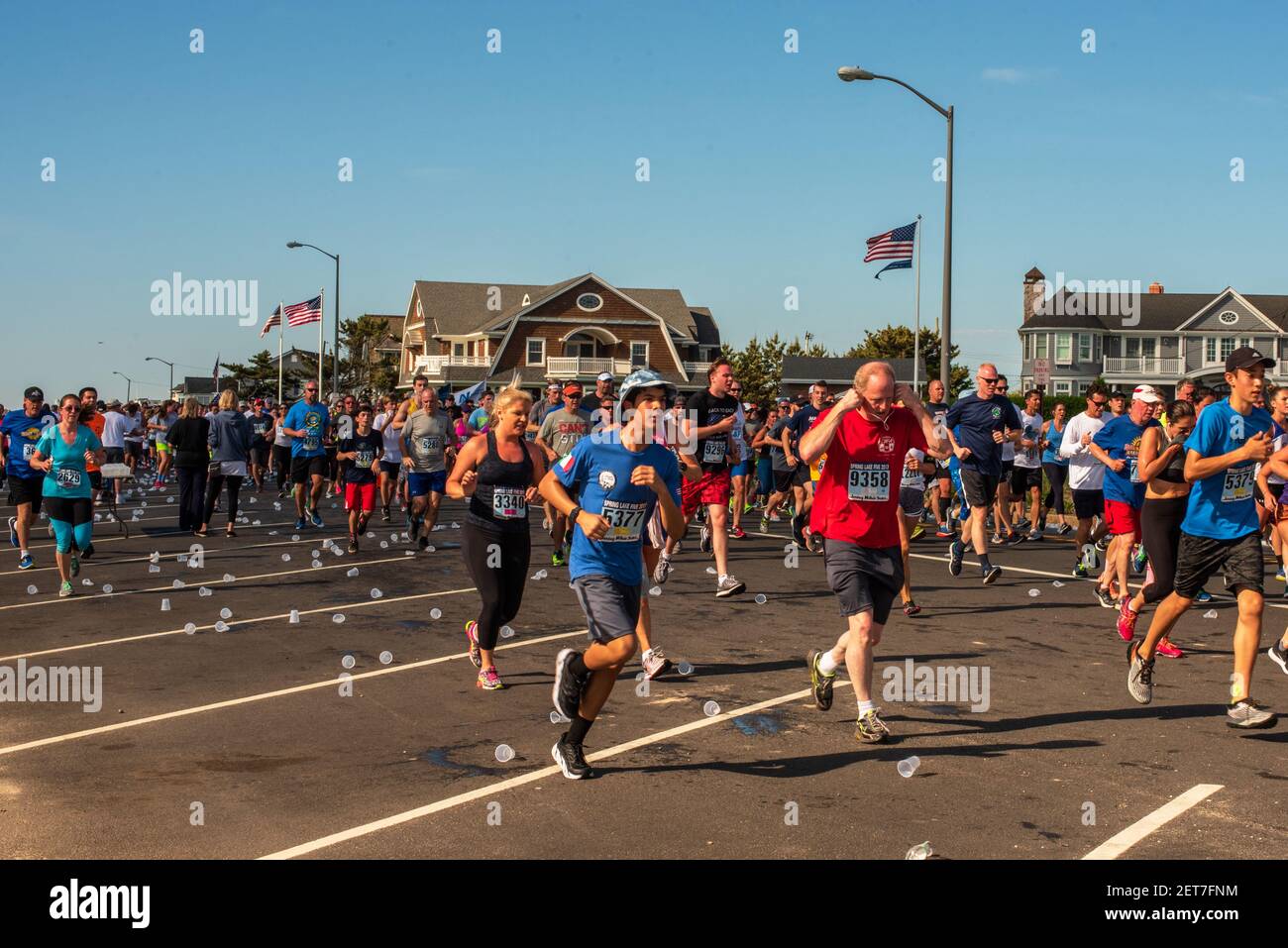 Spring Lake, NJ, USA - 27. Mai 2017. Marathonläufer ververwerfen Wasserbecher, während sie mit dem Rennen weitermachen Stockfoto