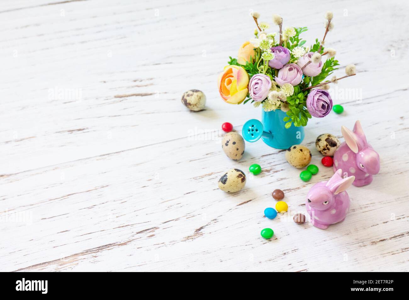 Fröhlicher Osterhintergrund mit Frühlingsblumen, ostereiern, Süßigkeiten und osterhasen auf weißem Holzhintergrund. Speicherplatz kopieren. Stockfoto