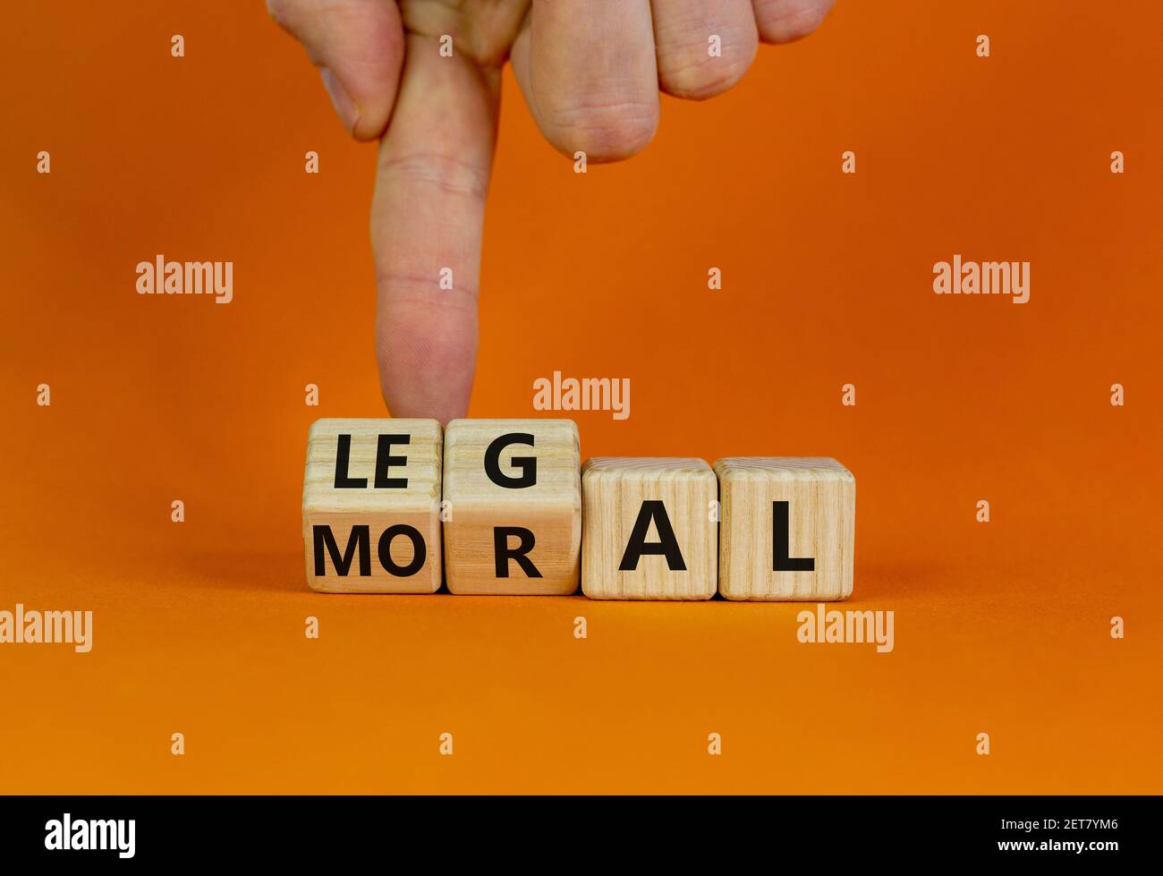 Moralisches oder rechtliches Symbol. Businessman Hand dreht Holzwürfel und ändert das Wort 'oral' zu 'legal' auf einem schönen orangefarbenen Tisch, orangefarbenem Hintergrund. Bus Stockfoto