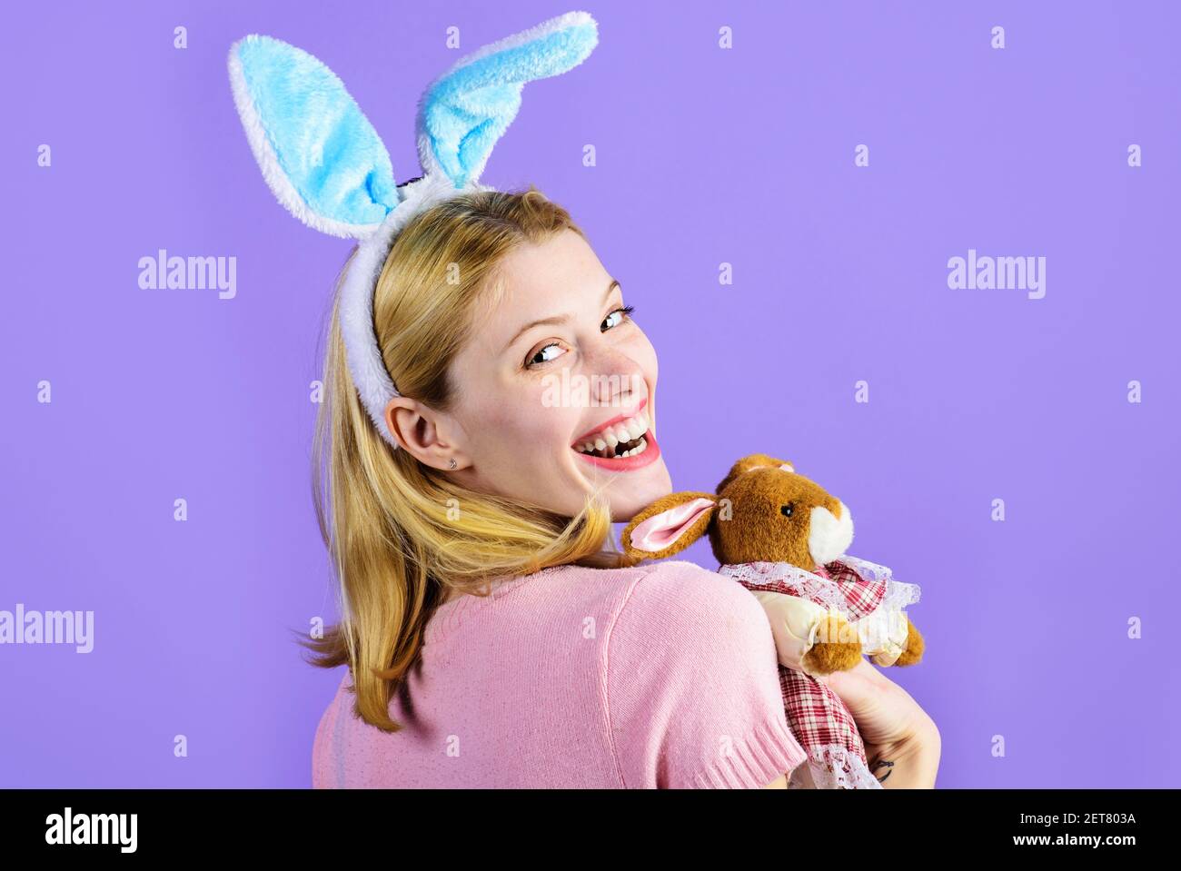 Frohe Ostern. Lächelndes Mädchen mit Plüsch Hase Spielzeug. Hübsche Frau mit Kaninchenohren. Stockfoto