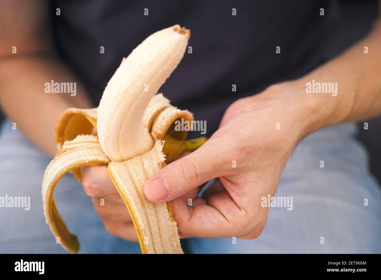 Ein Mann schält eine frische Banane. Geringe Schärfentiefe. Nahaufnahme. Stockfoto