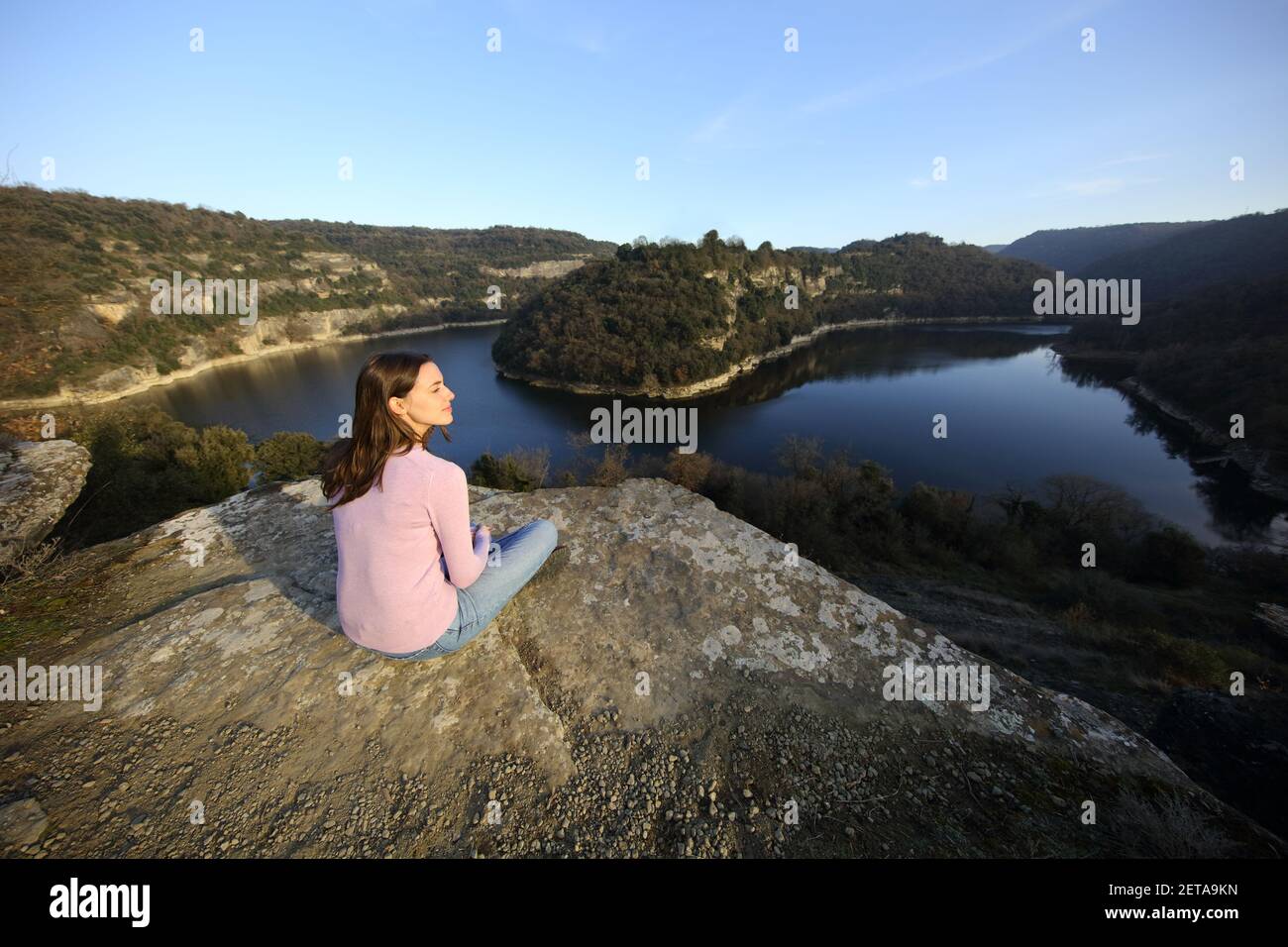 Entspannte Frau sitzen betrachtend Natur neben einem Fluss in der Berg Stockfoto