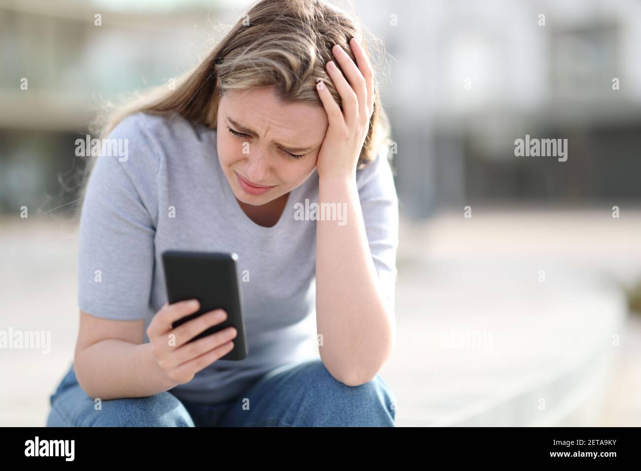 Trauriger Teenager, der schlechte Nachrichten auf dem Handy überprüft, beschwert sich allein Auf der Straße Stockfoto