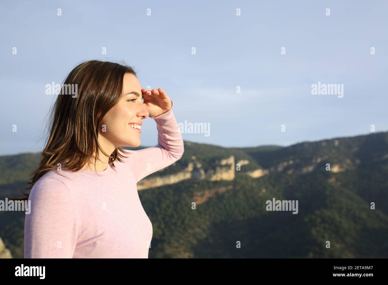 Profil einer glücklichen Frau, die sich mit Hand auf die Zukunft freut Stirn betrachtende Ansichten in den Berg Stockfoto