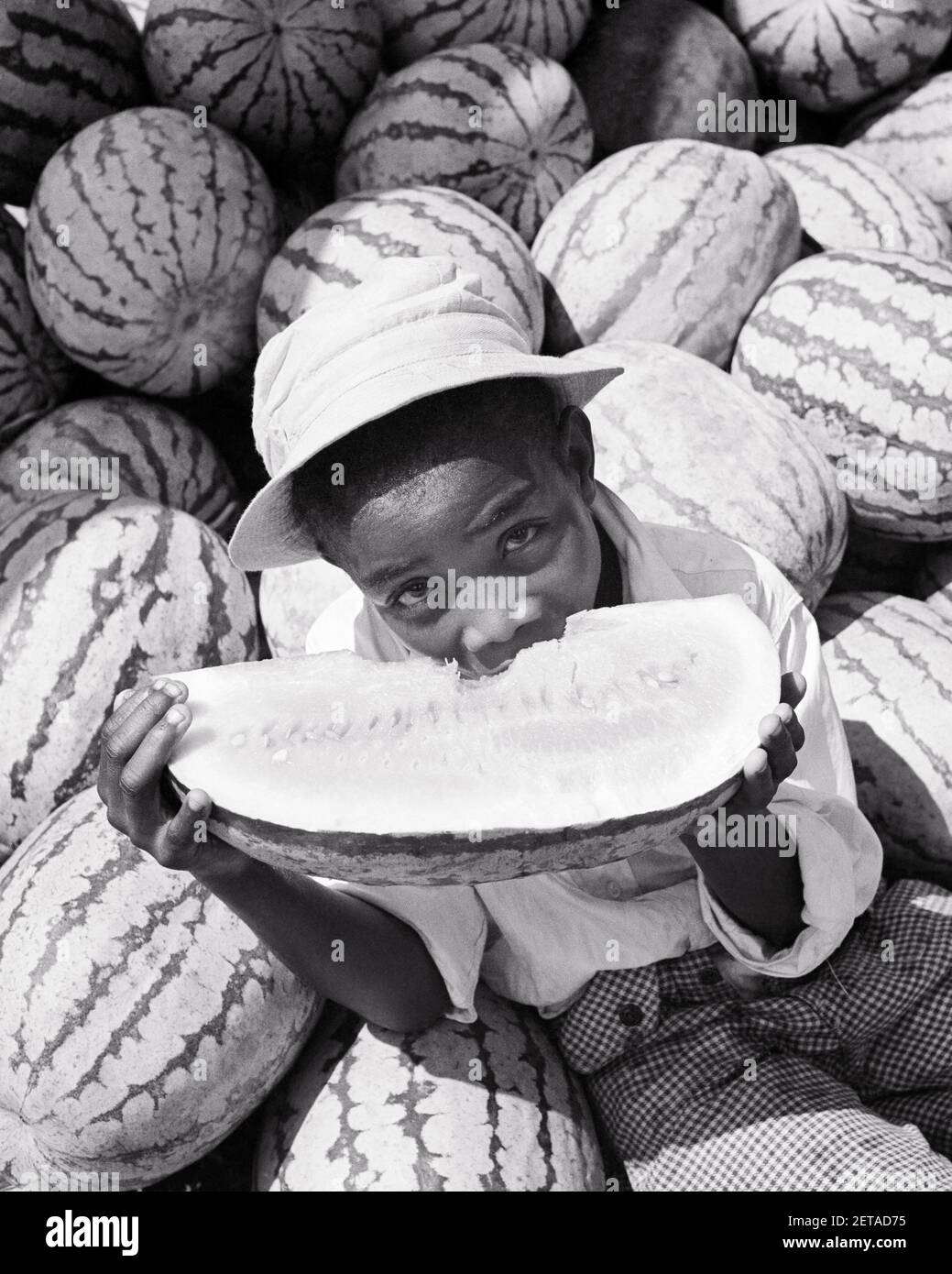 1930S AFROAMERIKANISCHER JUNGE, DER EIN STÜCK WASSERMELONE ISST UND DIE KAMERA ANSCHAUT - N816 LAN001 HARS NORTH AMERICAN SLICE HAPPINESS AFRO-AMERIKANER AFROAMERIKANER ERNÄHRUNG SÜDOST SCHWARZ ETHNIZITÄT SÜDLICHEN WASSERMELONE MELONEN MELONE WASSERMELONEN VERBRAUCHEN KONSUMIERENDE NAHRUNG OFFENSIVE JUGENDLICHE POLITISCH FALSCH STEREOTYPISCHE SCHWARZ UND WEISS ALTMODISCHE AFROAMERIKANER Stockfoto