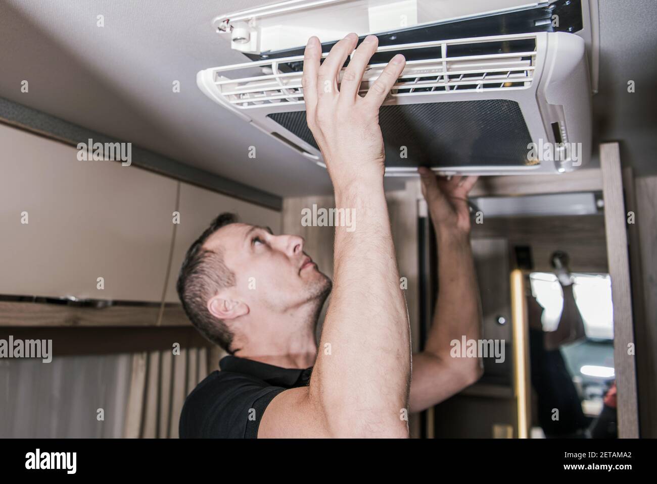 Kaukasischer RV-Gerätesechniker in seiner 40s bei der Arbeit. Auf der Suche nach einem potenziellen Problem mit der Klimaanlage Einheit im Wohnmobil. Thema der Wohnmobil-Branche. Stockfoto