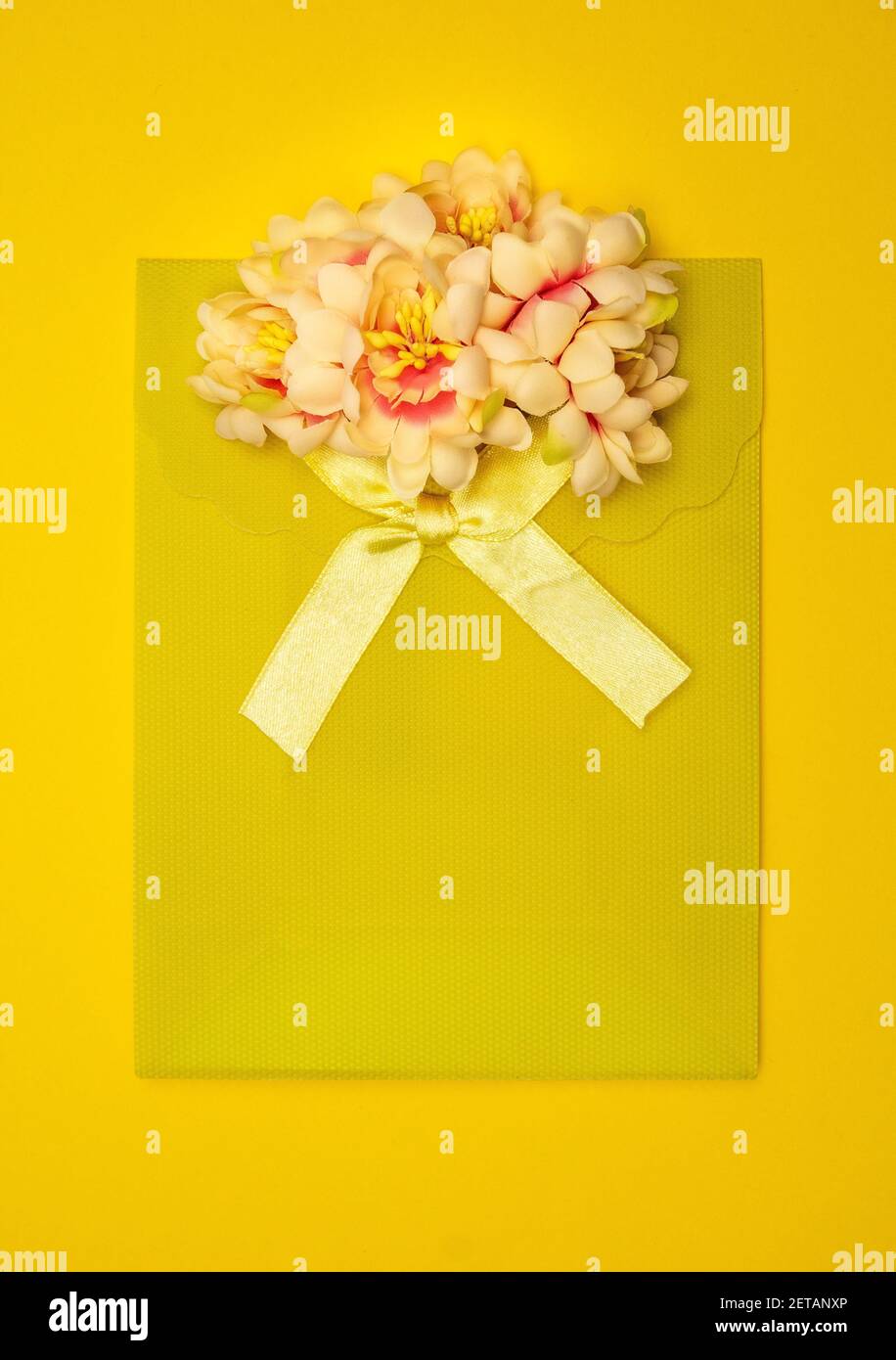 Gelbe Geschenktasche mit gelbem Band und schönen Blumen auf der Oberseite. Stockfoto