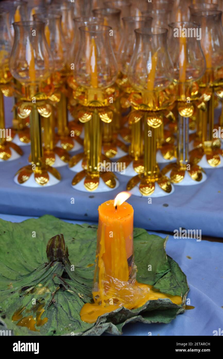 Buddha Tag in Bangkok, Thailand - Visakha Bucha Tag im Thai Tempel - brennende große gelbe Kerze mit vielen Kerzen in den goldenen Kerzenhaltern angezündet. Stockfoto