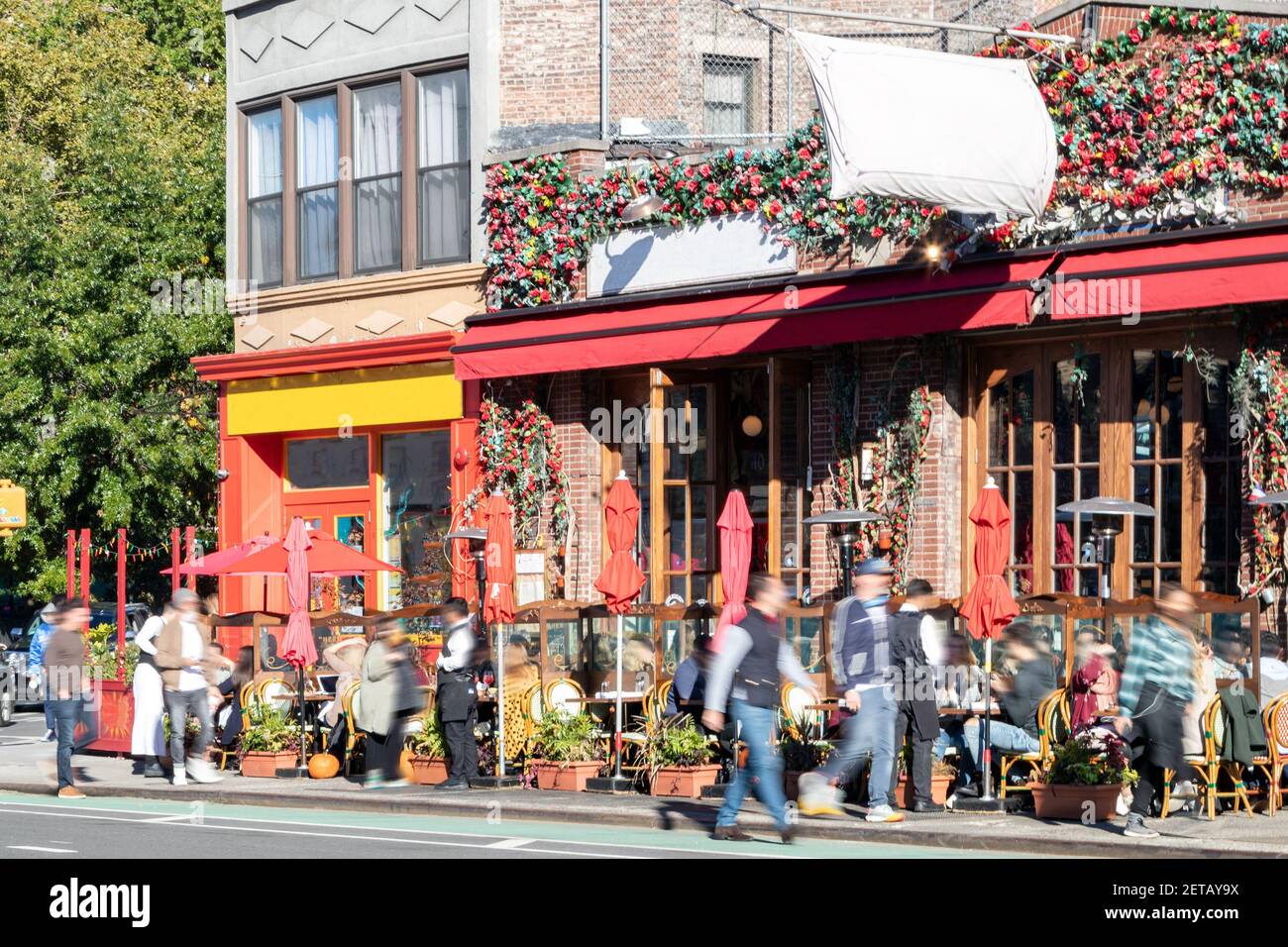 Belebte Straßenszene mit Menschenmassen in Restaurants mit Tische im Freien an der 7th Avenue im West Village Von New York City NYC Stockfoto
