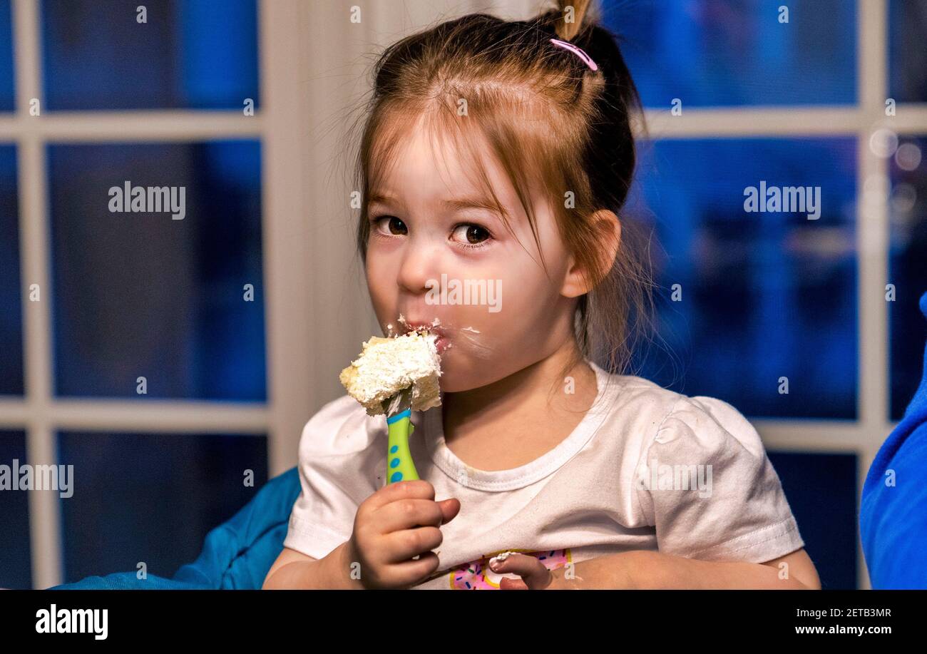 Zwei Jahre alt genießt ihren Geburtstagskuchen auf einer Gabel Stockfoto